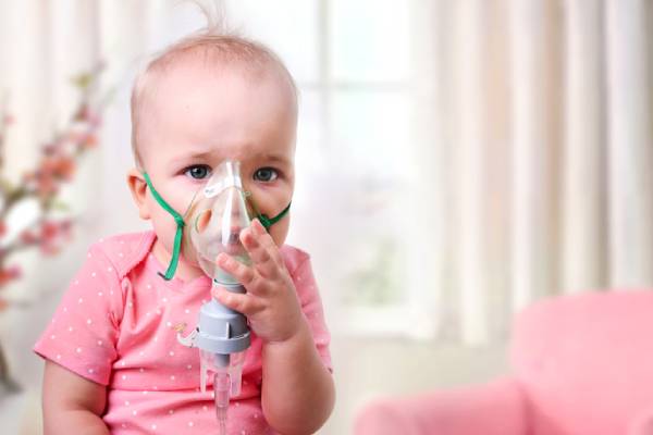 A baby receiving nebulization treatment with a mask, highlighting respiratory care for infants and children.